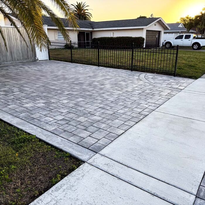 Finished concrete pavers over reinforced concrete base. For this project, we were creating a foundation for a paver overlay. First, a reinforced concrete curb was installed which gave us our form for the driveway pavers to sit in. That foundation slab was made up of 4000lb concrete not less than 5 inches in the field and 7 inches on the thickened edge. Reinforced with .29 on 6 inch steel mesh with #5 rebar on the leading edges. This slab, on its own, will last for generations. The finish for this project was an overlay of pavers that gave us a finish that will be resilient and beautiful for generations to come.