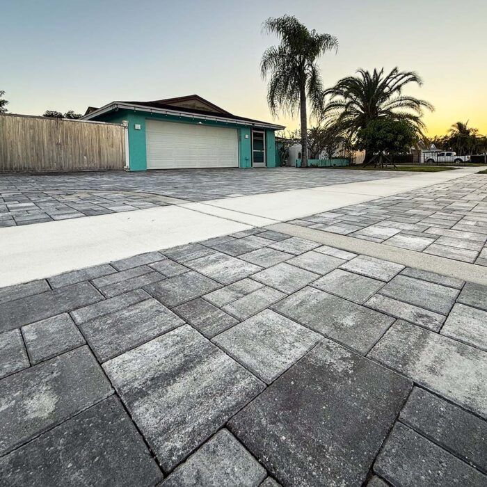 Finished concrete pavers over reinforced concrete base. For this project, we were creating a foundation for a paver overlay. First, a reinforced concrete curb was installed which gave us our form for the driveway pavers to sit in. That foundation slab was made up of 4000lb concrete not less than 5 inches in the field and 7 inches on the thickened edge. Reinforced with .29 on 6 inch steel mesh with #5 rebar on the leading edges. This slab, on its own, will last for generations. The finish for this project was an overlay of pavers that gave us a finish that will be resilient and beautiful for generations to come.