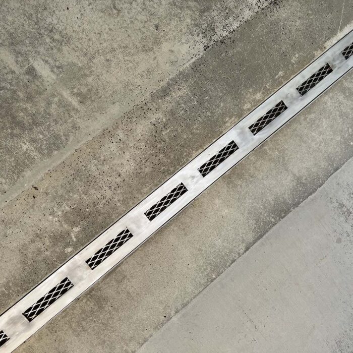 Trench drain with finished stainless steel grate. Trench drain after concrete pour with only stainless steel rails and grate visible. Custom Stainless Steel Trench/Channel Drain utilizing a negative hard foam forming system.